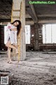 A woman leaning against a ladder in an abandoned building.