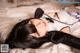 A woman laying on top of a bed wearing black gloves.