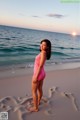 A woman in a pink bathing suit standing on the beach.