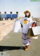 A woman in a white sweatshirt and a yellow hat holding shopping bags.