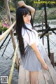 A woman standing on a wooden bridge next to a body of water.