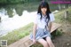 A young woman sitting on a wooden bench by a lake.