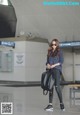 A woman in a plaid shirt and black pants is walking through an airport.