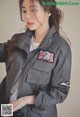 A woman wearing a gray jacket with patches on it.