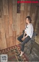 A woman sitting on a chair in front of a wooden wall.