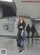 A woman is walking through an airport with a black bag.