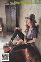 A woman sitting on top of a brown couch wearing a hat.