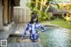 A woman in a blue and white floral swimsuit sitting on a wooden dock.