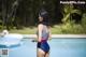 A woman in a bathing suit standing next to a swimming pool.