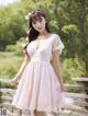 A woman in a pink dress standing on a wooden bridge.