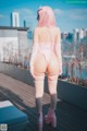 A woman with pink hair standing on a wooden deck.