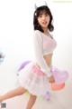 A woman in a white sweater and pink tutu posing for a picture.