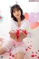 A young woman sitting on the floor holding a bunch of balloons.