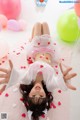 A little girl laying on the floor surrounded by balloons.