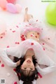 A little girl laying on the floor surrounded by balloons.