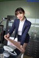 A woman in a business suit standing next to a desk.