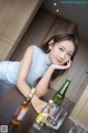 A woman sitting at a table with a bottle of beer.