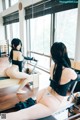 A woman sitting on a reformer in a gym.