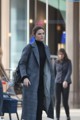 A woman walking down the street in a black and white coat.