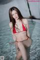 A woman in a red bikini sitting in a pool.