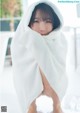 A woman wrapped in a white towel is posing for a picture.