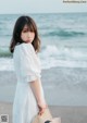 A woman in a white dress standing on the beach.