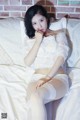 A woman in a white lingerie sitting on a bed.