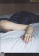 A woman laying on a bed with a ring on her finger.