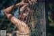 A woman in a bikini leaning against a fence.