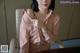 A woman in a pink shirt sitting at a desk.